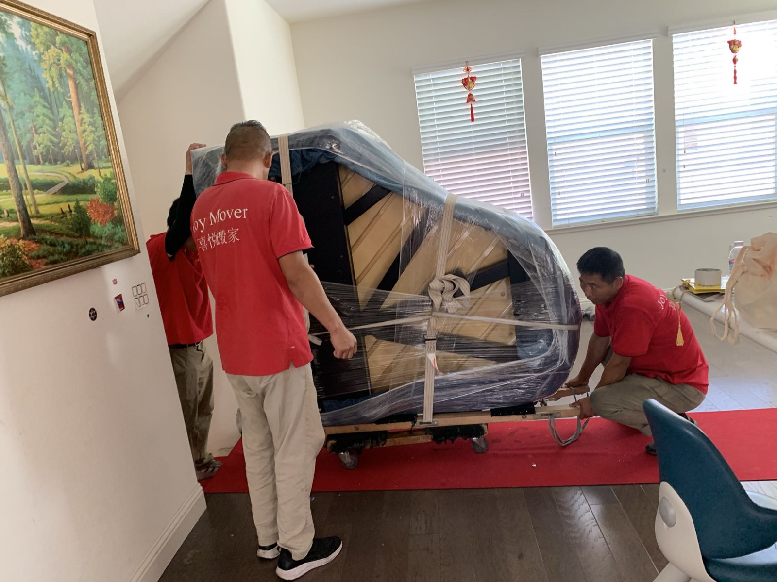 Specialist crew carefully wrapping and moving a piano